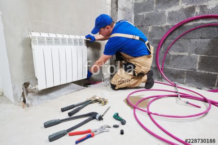 plumber at work. Installing water heating radiator